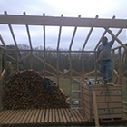 Carpenter standing on first bins of hardwood readied for drying.